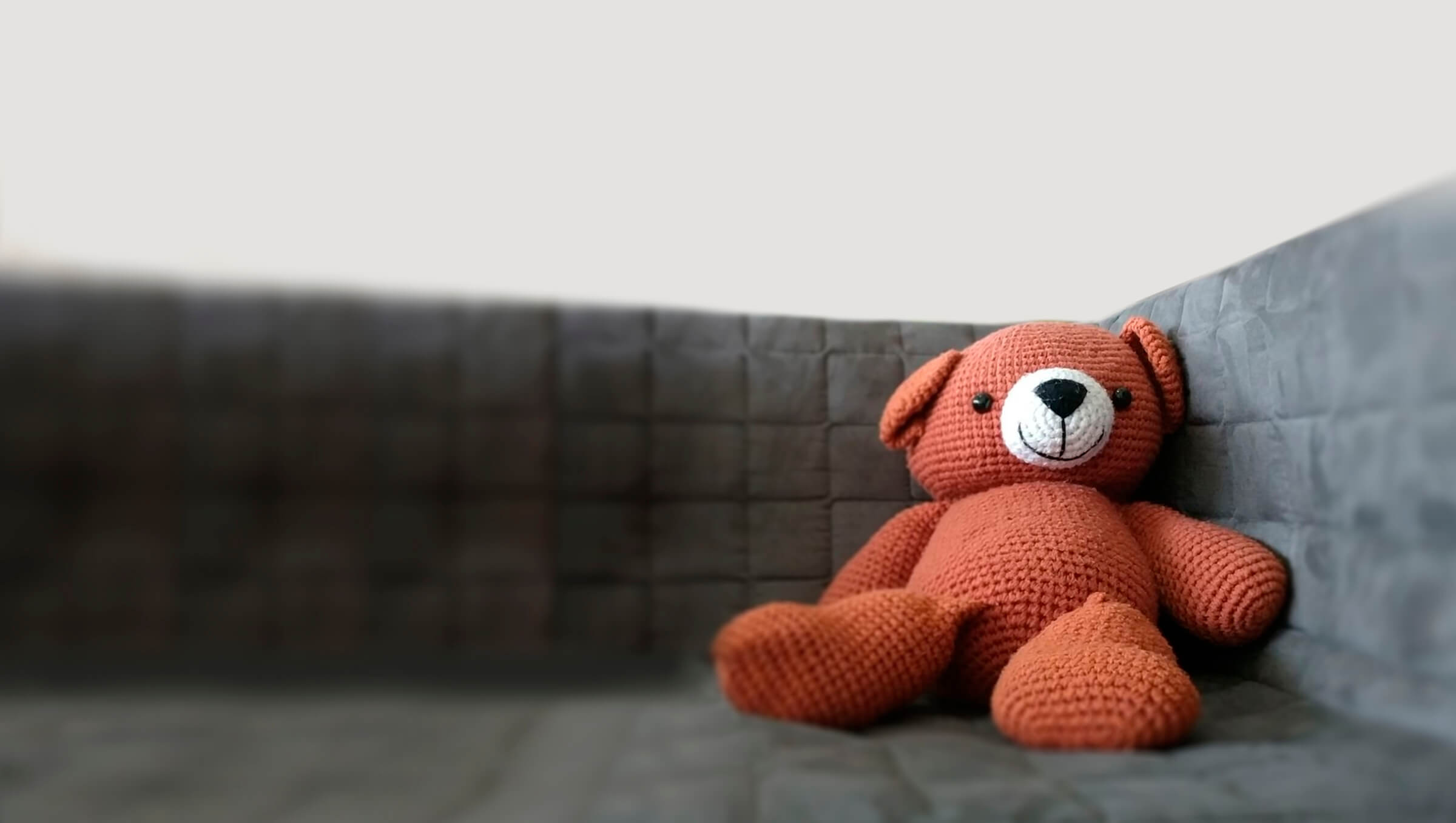 Smiling salmon pink coloured teddy bear sat on safe