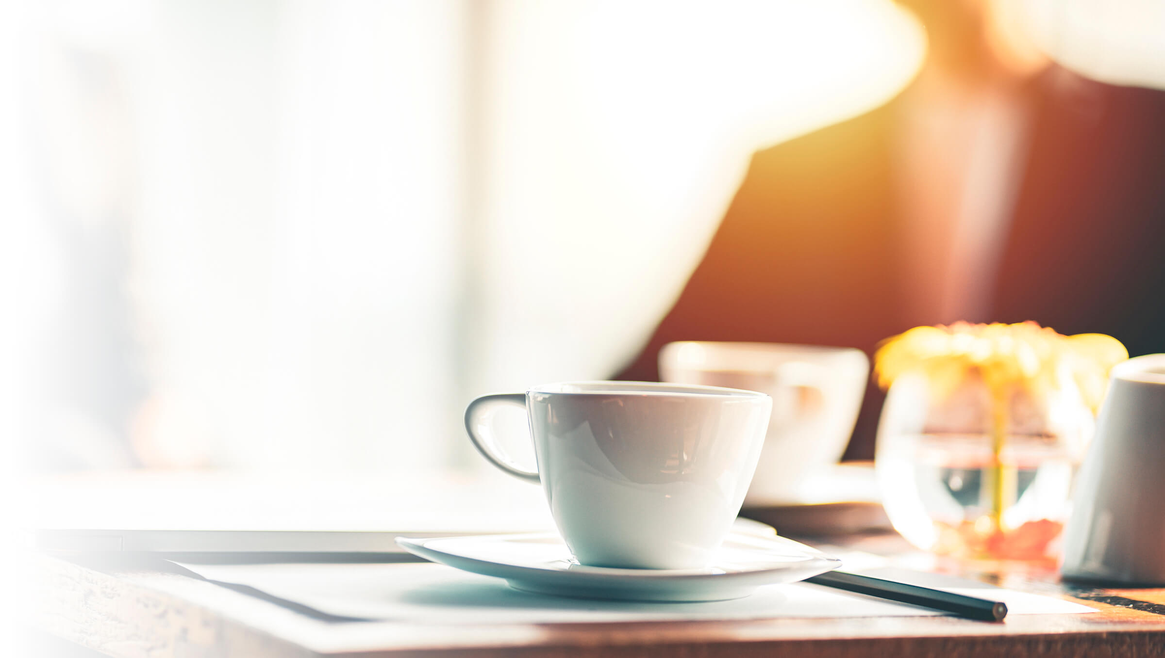 Coffee cups on an office desk with soft focus person behind